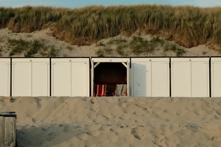 Weiße Strandhütten vor den Dünen