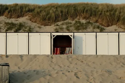 White beach huts in front of the dunes